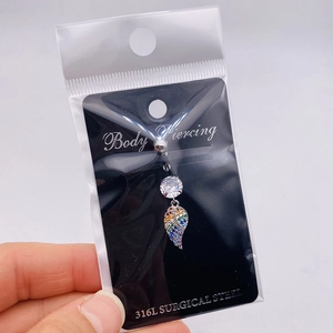 Detail of 316L surgical steel belly ring with colorful leaf pendant in packaging