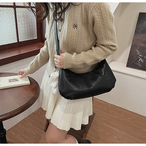 Detail of a soft black PU leather shoulder bag featuring a cute white plush bear pendant