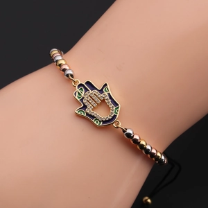 Macro detail of the Hamsa hand charm with purple enamel and pave-set zircons on the wrist