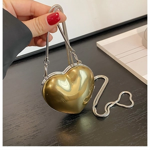 Detailed close-up of a heart-shaped gold mirror crossbody bag with a silver chain strap