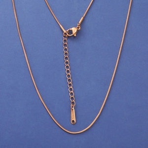 Detalle de collar de cadena de serpiente oro rosa con cierre de mosquetón y placa S-STEEL