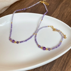 Detailed view of zircon amethyst beaded necklace and bracelet set on a white tray
