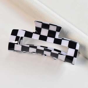 Detail of medium black and white checkered acetate hair claw clip on clean background