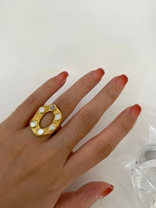 Close-up of 18K gold plated hollow oval ring with inlaid white shell on finger