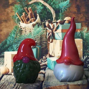 Close-up of festive Christmas gnomes in glossy red and green finish on a rustic holiday table