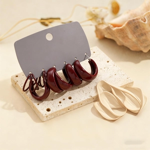 Macro view of six pieces set dark red geometric hoop earrings on a stone display