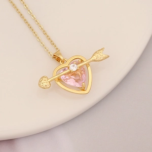 Detail of 18K gold plated necklace with pink heart gem and cupid arrow on ceramic plate