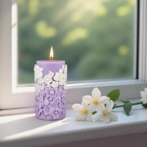 Floral cylinder aromatherapy candle with purple relief flowers on a sunny windowsill