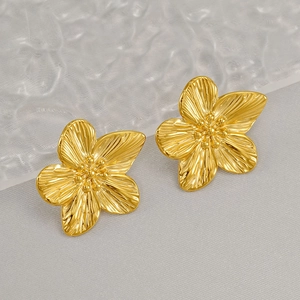 Macro shot of 3D gold-plated flower stud earrings with detailed brushed metal texture
