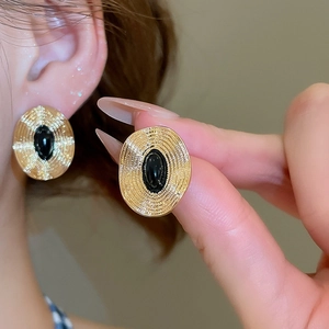 Nahaufnahme von Vintage Gold-Ohrringen mit schwarzem Stein und Strahlen-Struktur