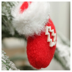 Macro view of a red and white plush Christmas stocking ornament hanging on a snowy branch