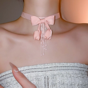 Elegant pink fabric bow choker necklace featuring tassel charms and bead details on a model