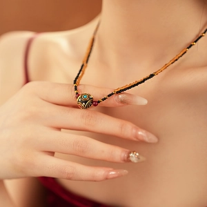 Dettaglio di una collana di perline placcata oro con motivi in smalto colorato etnico