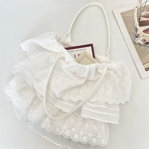 Dettaglio di balze in pizzo bianco e delicati ricami floreali sulla borsa tote