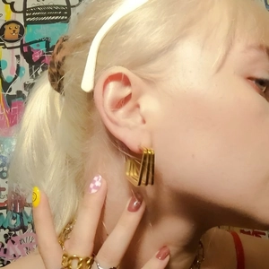 Vintage triple-line geometric earrings in gold finish worn by model on graffiti background