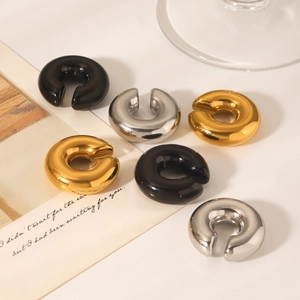 Detailed view of polished gold, silver, and black hollow ear cuffs on aesthetic background