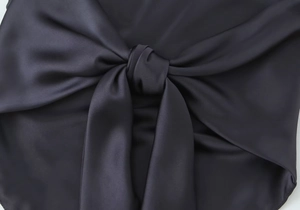 Gros plan détaillé du tissu satiné bleu marine montrant la texture lisse et le nœud central