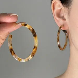 Close-up of large tortoiseshell resin hoop earrings with a classic leopard pattern