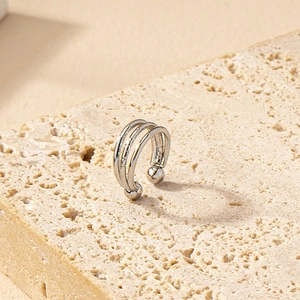 Detail view of a silver multi-layer ear cuff with polished finish on a stone background