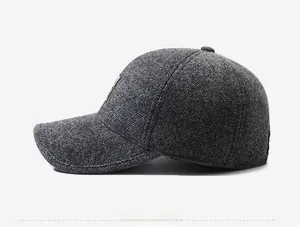 Detail showing dark grey herringbone texture and leather emblem on the winter baseball cap