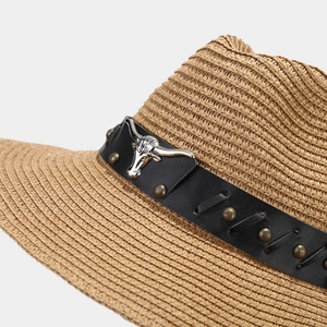 Macro detail of straw cowboy hat with black leather band and silver longhorn metal stud