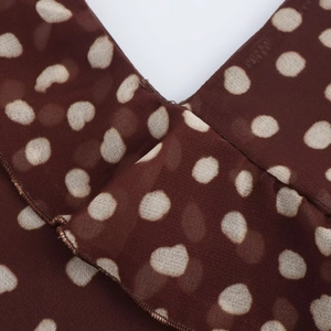 Macro detail of brown chiffon fabric with beige polka dots and fine stitching textures