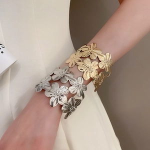 Close-up of golden and silver metal flower cuff bracelet with brushed hammered texture