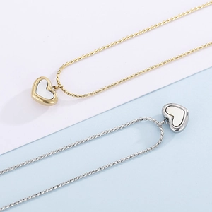 Détail de pendentifs cœur en nacre blanche sur des colliers en maille serpent bicolore