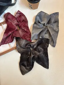 Close-up of vintage satin scrunchies in burgundy, blue and black with marble pattern