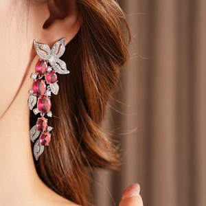 Gros plan de boucles d'oreilles fleurs et feuilles avec rubis rouges et zircons