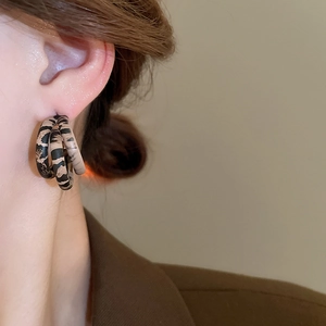 Close-up of triple layered leopard print hoop earrings made of polished resin