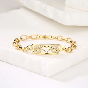 Macro view of gold bracelet featuring micro-paved smiley faces and a cutout heart detail