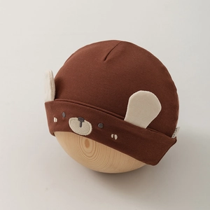 Détail du bonnet pour bébé ours marron avec oreilles 3D et broderie sur un moule en bois