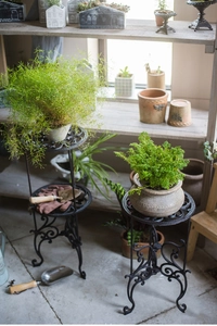 Détail de deux supports de plantes en fonte noir mat avec des motifs vintage pour jardins