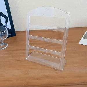 Detailed view of 4-tier clear acrylic earring display stand with L-shaped base on wood