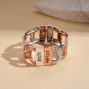 Macro view of retro hollow geometric cross stretch bracelet with engraved words on metal