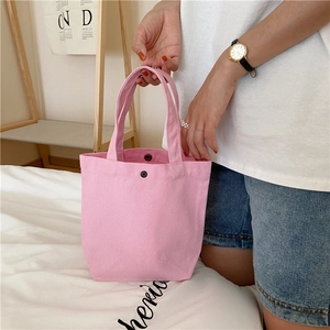 Detail of pink canvas lunch bag featuring a secure magnetic snap button closure