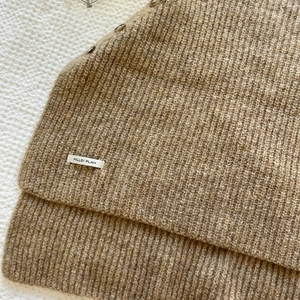 Macro shot of khaki knit texture with vertical ribs and HILLDI PLAN brand label