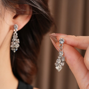 Close-up of elegant silver drop earrings with clear crystals on a textured fabric