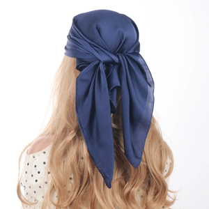 Rear view of model wearing a navy blue satin silk square scarf with elegant drape