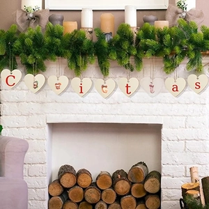 Hanging wooden heart banner with red Christmas lettering over a cozy white fireplace