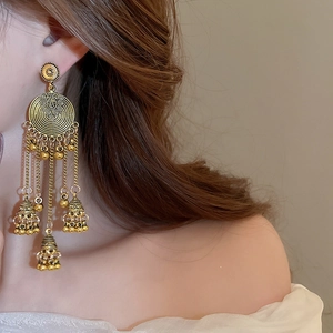 Close-up of vintage tribal gold tassel earrings with intricate engraved circular disks
