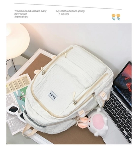 Détail du sac à dos blanc crème à texture bulles avec peluche lapin et boucle latérale