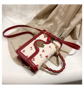 Detail of red and white cherry print bag with camellia lock and metal cherry charm