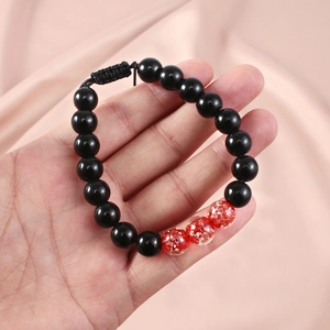 Detail of adjustable beaded bracelet with black onyx beads and red gold foil glass accents