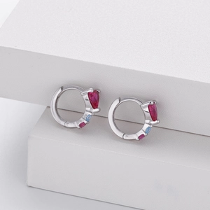 Macro view of S925 silver hoop earrings featuring pear-cut red and blue gemstones