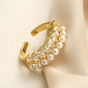 Gold plated geometric open ring with cubic zirconia and pearls on beige velvet