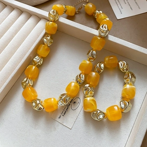 Detail of amber acrylic beads and golden irregular metal charms in a jewelry display box