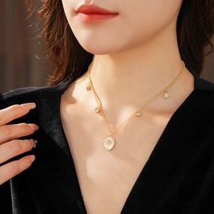 Dettaglio della collana in madreperla dorata con ciondoli a stella e diamante su modella