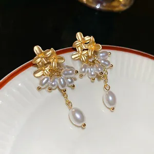 Elegant gold flower pearl tassel earrings with French vintage style on ceramic tray